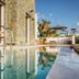 Pelican Bay Hotel in Platis Gialos with a stone terrace and pool reflecting the building and sky