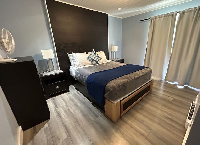 Riverside Resort & Rv Park room in Qualicum Beach with a bed, nightstands and large curtained window