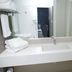 Hotel Verona Tower in Divinópolis bathroom with white sink, mirror, towels and floral decor