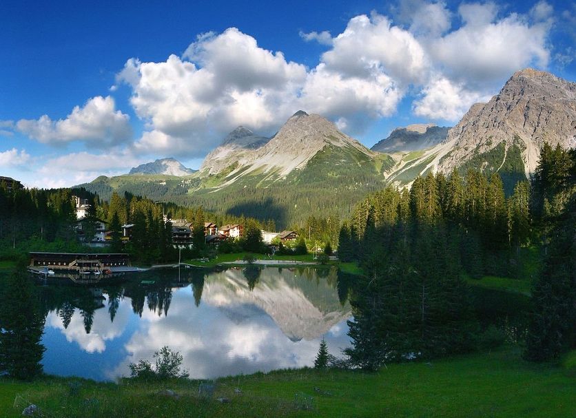 Hotel Seehof-Arosa in Arosa with mountain lake reflection and forested peaks under a blue sky