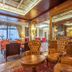 Abano Ritz Hotel Terme in Abano Terme, ornate lounge with leather chairs, round table and mirrored wood paneling