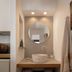 Porto Kaza Sitia bathroom vanity with round mirror, vessel sink, open towels and shower curtain