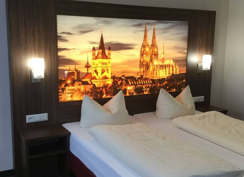 Hotel Am Freischütz room in Hürth with twin beds and illuminated Cologne cathedral wall art
