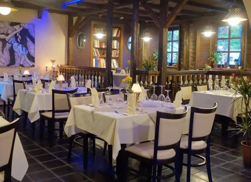 Landhotel Burkartsmühle in Hofheim dining room with set tables, bookshelves, and warm lighting