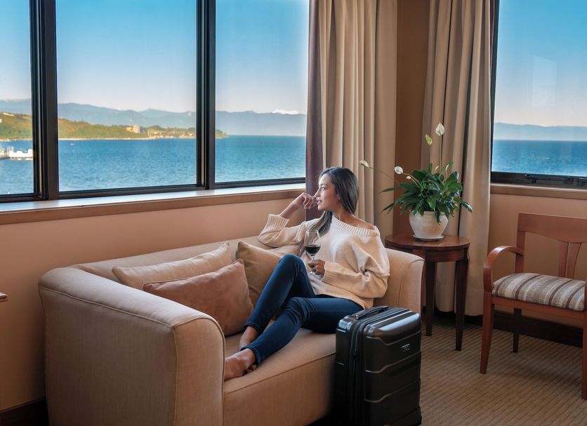 Guest relaxing in a Gran Pacifico room with large windows and bay views in Puerto Montt