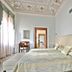 Hotel Palazzo Vitturi Venice guest room with ornate ceiling, king bed, window light and vanity