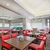 Hilton Garden Inn Livermore dining area with red chairs, wood tables, and large windows in Livermore