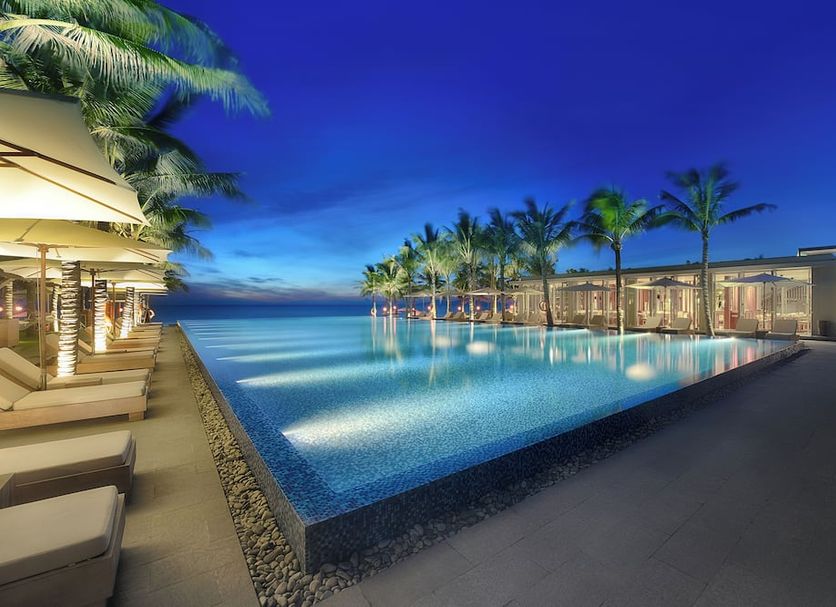 Naman Retreat Da Nang infinity pool with ocean view at dusk and palm trees