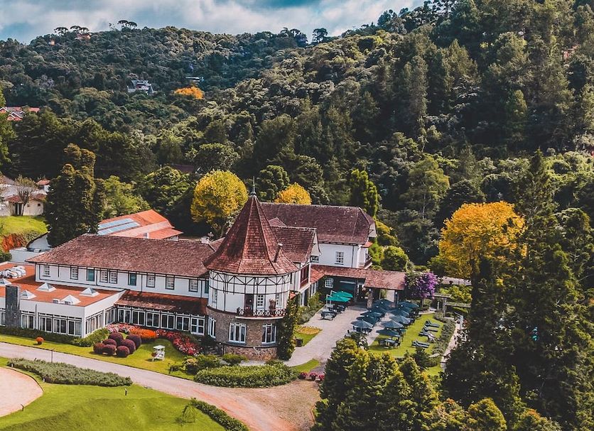 Hotel Vila Inglesa in Campos do Jordão set amid lush forested hills with landscaped gardens and parking