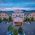 Fairfield Inn & Suites by Marriott Burlington exterior at dusk with parking lot and mountain backdrop