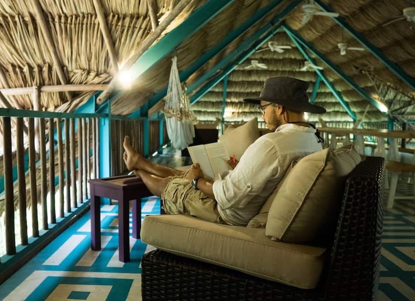 Jungle Lodge Tikal Hostal in Tikal, guest relaxing on an upper-level balcony with jungle view