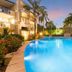 Montpellier Boutique Resort in Noosaville with a lit outdoor pool, palm trees, and twilight sky