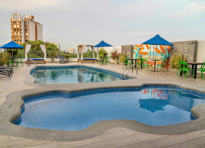Howard Johnson by Wyndham Barranquilla Versalles rooftop pool deck with lounge chairs and umbrellas