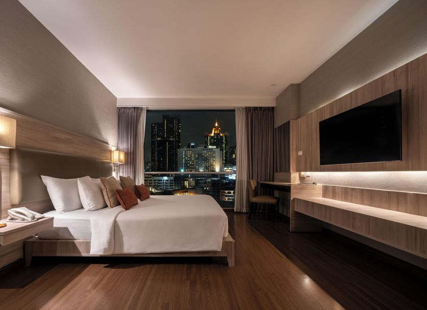 Adelphi Suites Bangkok guest room with city skyline view and wall-mounted TV