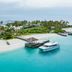 Hard Rock Hotel Maldives in Malé: overwater dock, white sand beach, turquoise lagoon, and a boat