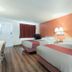 Motel 6 Newport News, VA room with two beds, red accent wall, and wood-look flooring