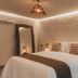 Pousada Topázio in Fernando de Noronha bedroom with bed, full-length mirror and warm woven lights