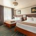 The Flat Iron Hotel, Asheville guest room with two beds, lamps, and large window curtains