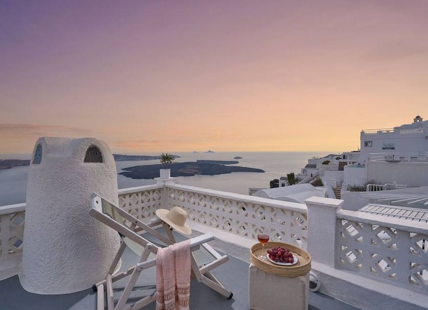 Santorini Mansion at Imerovigli terrace with lounge chairs and sunset sea view in Imerovigli
