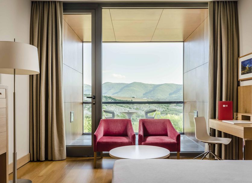 Exe Las Margas Golf Hotel in Latas room with balcony and mountain views, two pink chairs and desk