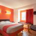 Motel 6 El Paso - Southeast room with bed, orange accent wall, window bench and red curtains