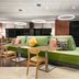 Home2 Suites by Hilton Salt Lake City/Layton lobby seating area with green sectional and tables in Layton