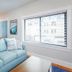 Surf House in Hampton: bright guest room with light blue sofa, coffee table, and large window blinds