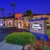 Hampton Inn & Suites Ontario exterior at dusk with palm trees, entrance drive, and illuminated sign