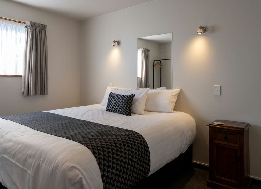 Asure Highpark Motor Inn Greymouth guest room with double bed, window, mirror and bedside lights