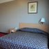 Great Eastern Hotel Quezon City guest room in Manila with bed, armchair, side table and framed wall art