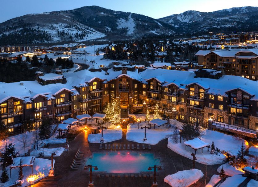 Waldorf Astoria Park City in Park City with snowy mountain views and illuminated outdoor pool at dusk