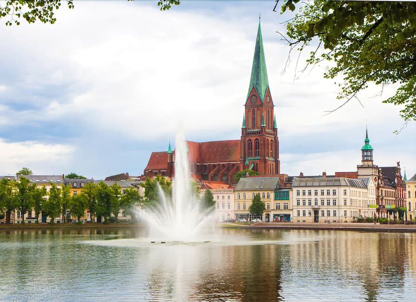 Pension Am Schloss in Schwerin with lake fountain and historic cathedral skyline