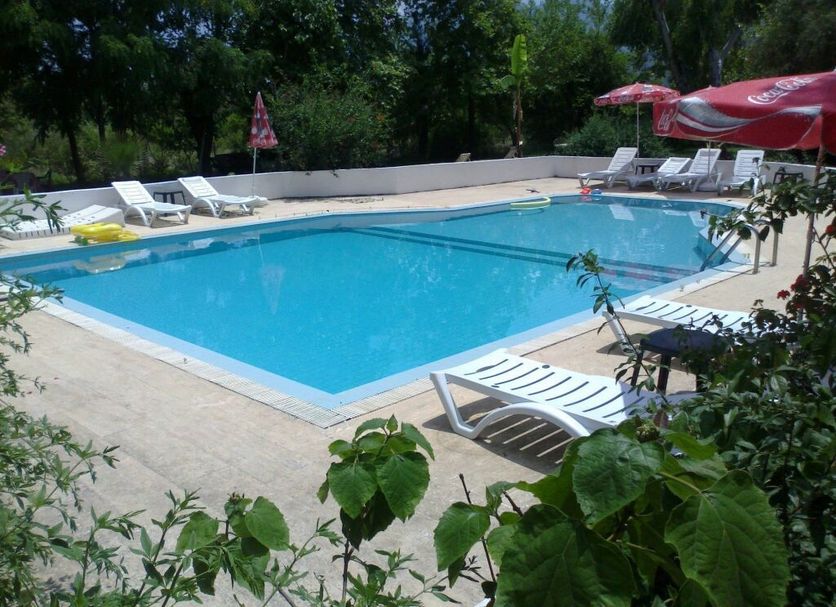 Fire pansiyon in Cirali: outdoor swimming pool with lounge chairs and umbrellas