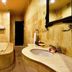 Dolphin Beach Bali in Banjar bathroom with beige stone tub, curved sink, and mirror