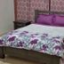Gabrielle's hotel room in Port Au Prince with a bed, purple pillows, and matching floral bedding