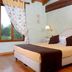 Albergo Antica Hostelleria room in Crema with double bed, wood beams, and window with floral curtain