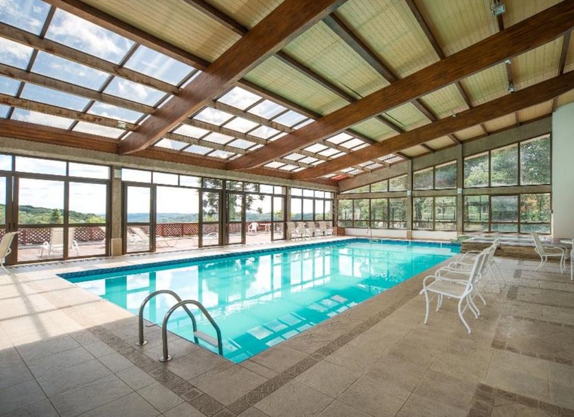 Sky Borges Hotel Alpenhaus - Gramado indoor pool with large windows and lounge chairs