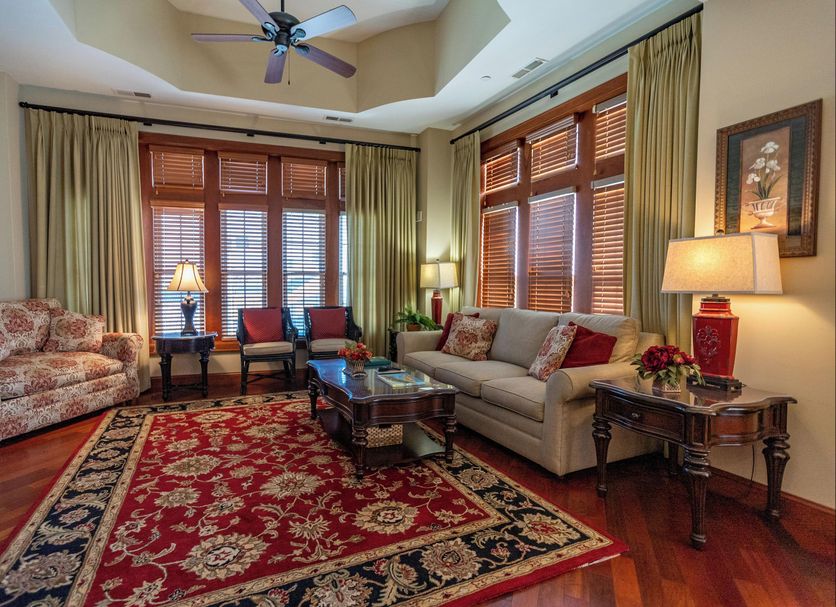 The Flanders Hotel, Ocean City living room with sofa, floral chairs, red rug, and tall windows