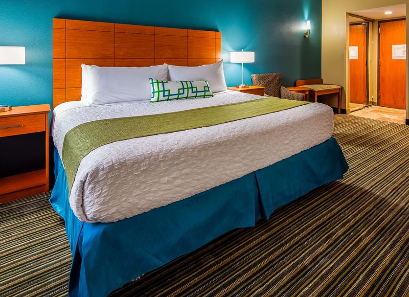 Best Western Warren Hotel room with king bed, teal walls, striped carpet, and bathroom doorway in Warren