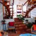 La Villa Des Violettes in Toulouse: interior staircase with wicker chairs, plants, and red cushions