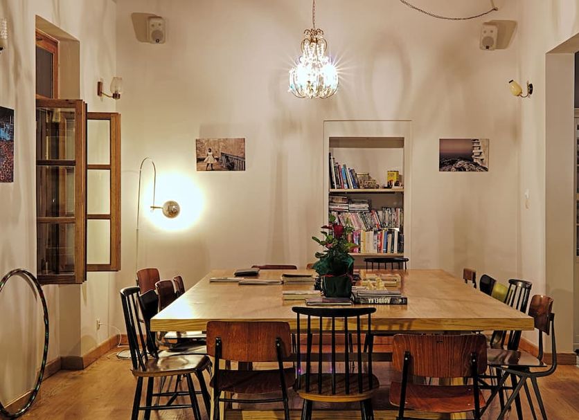 City Circus Athens dining room with long wooden table, chandelier, bookshelves and open French doors