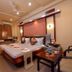 Hotel NavaRATNA Coimbatore guest room with king bed, wall-mounted TV, desk, and ceiling fan