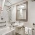 Red Roof Inn Greenville bathroom with bathtub, shower, sink, mirror, grab bars, and towels
