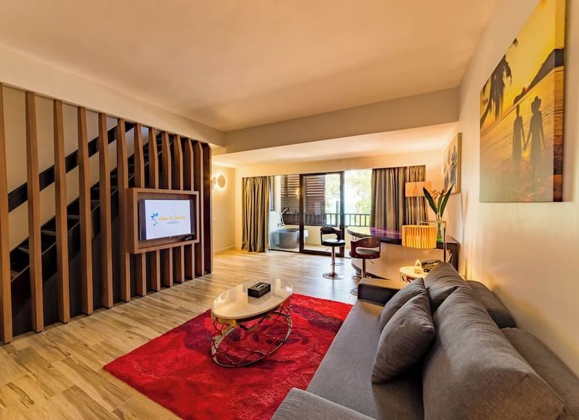 Sand & Sandals Desaru Beach Resort & Spa suite in Bandar Penawar with sofa, TV, and sea-view balcony