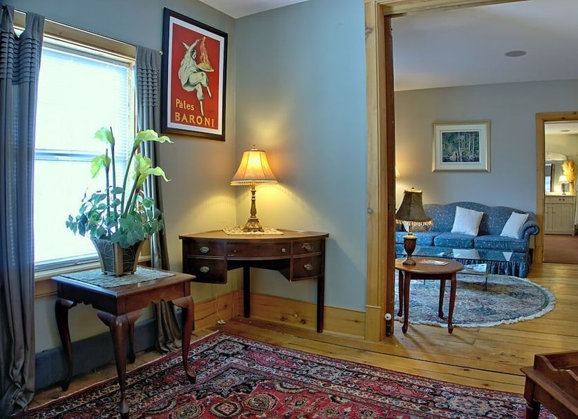 Emilyville Inn in Campbellford, guest room with desk, lamp, patterned rug and blue seating area