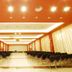 Hotel Club Astor in Ugento conference hall with rows of chairs and stage under bright ceiling lights