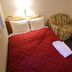Hotel New Gaia Tenjin Minami in Fukuoka guest room with red bedspread, armchair, and bedside table
