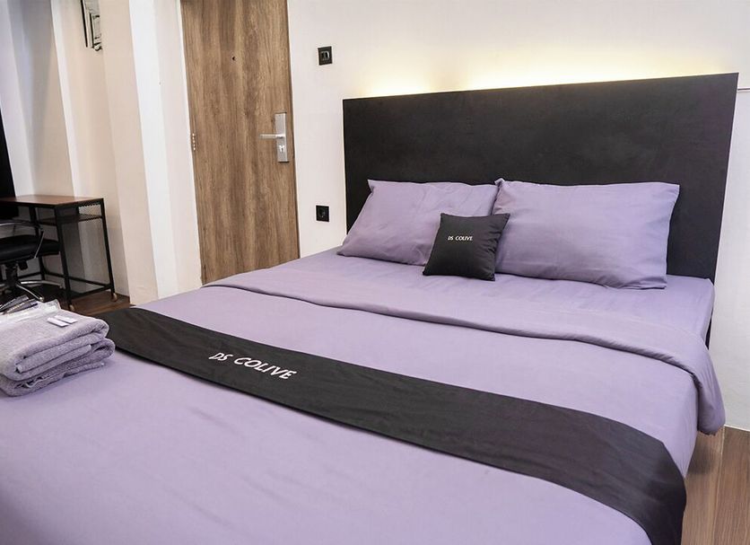 Ds Colive Sinabung, Semarang: minimalist bedroom with lavender bed, desk, chair and folded towels