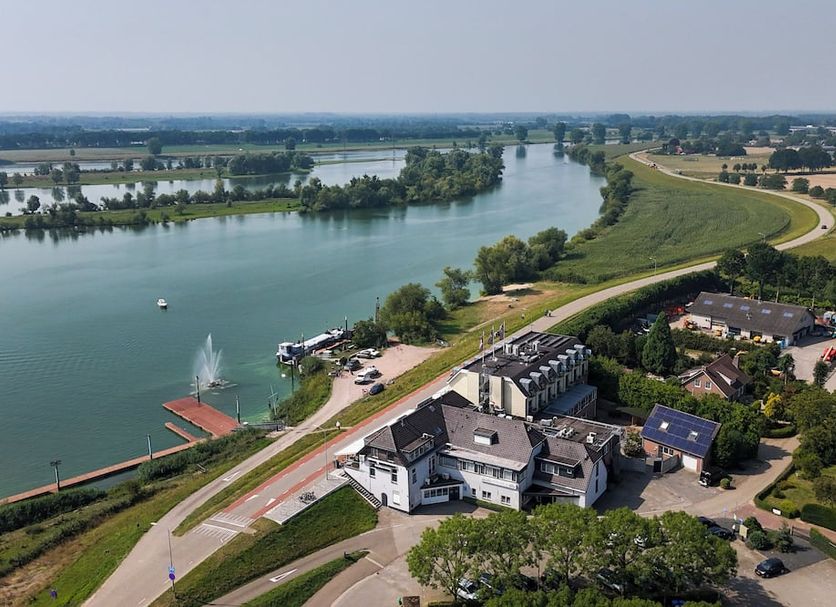 Hotel Hoogeerd by Flow in Wijchen with river views, a winding road, and waterfront grounds