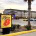 Super 8 by Wyndham Kenedy exterior with palm trees, parking lot, and entrance drive